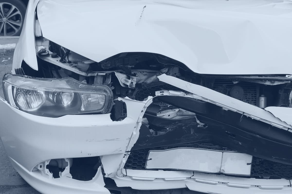 Close view of the same vehicle's front left corner, headlamp assembly exposed and the bumper reinforcement crushed.